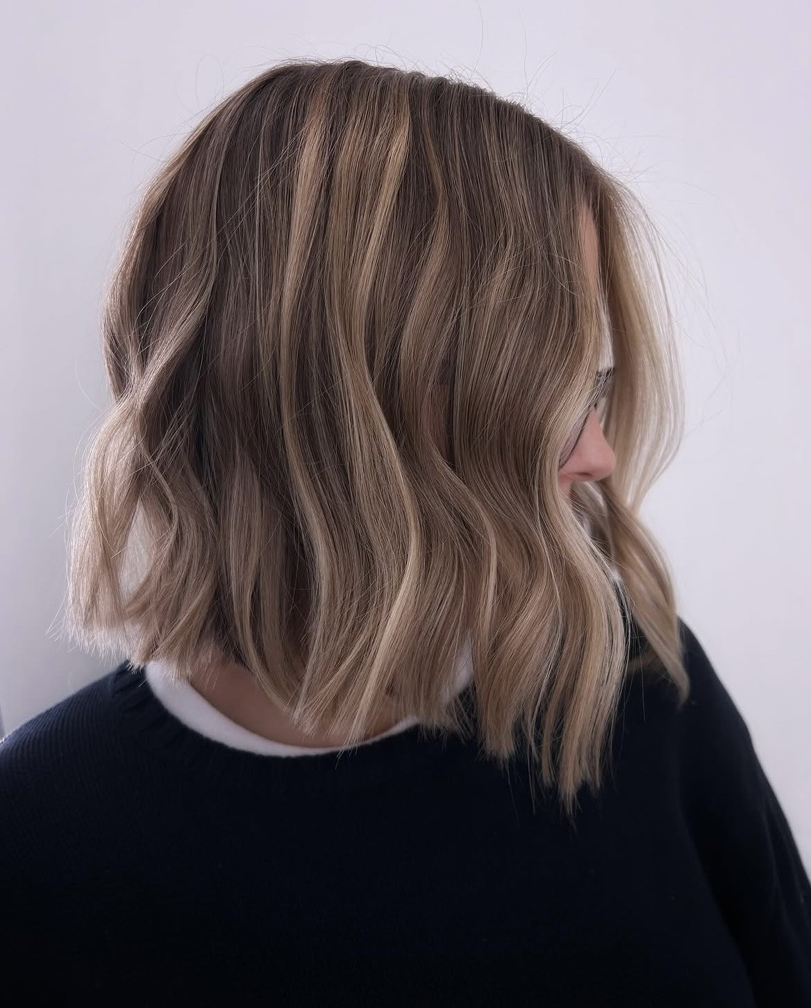 Textured blonde lob with soft waves and shadow-rooted colour, side profile