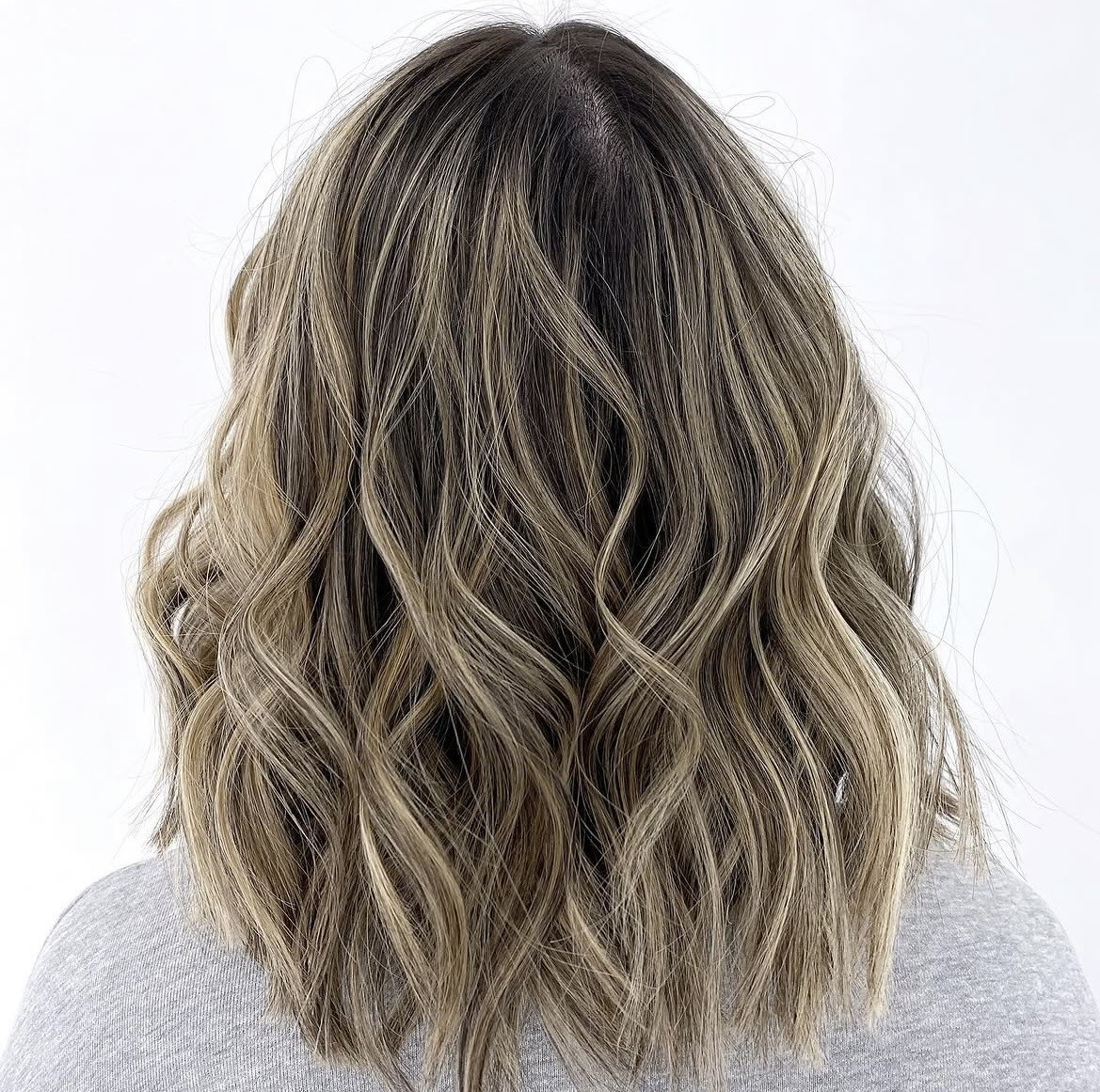Mid-length beachy waves with cool ash-blonde highlights over a dark root
